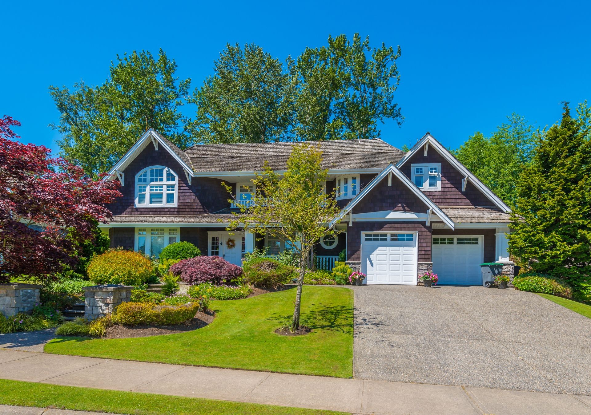 Big custom made luxury house with nicely landscaped and trimmed front yard and driveway to garage in the suburbs of Vancouver, Canada.